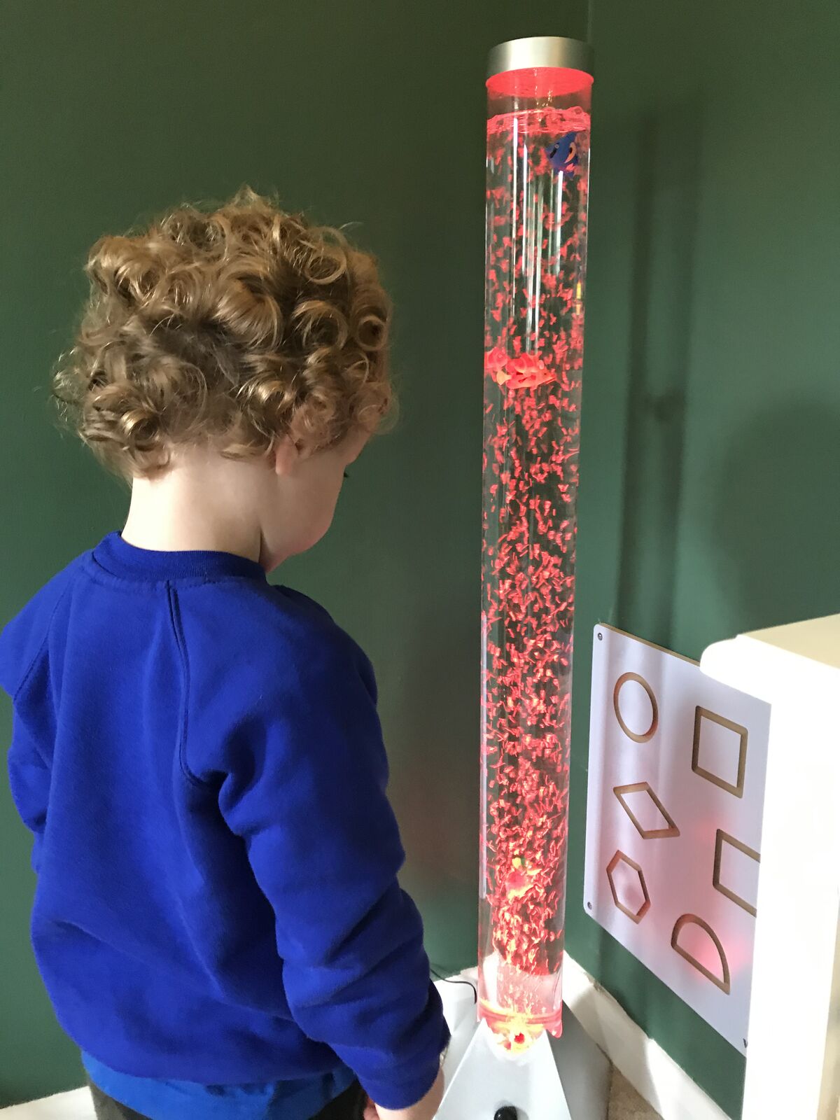A child watching a bubbling sensory tube filled with red glitter