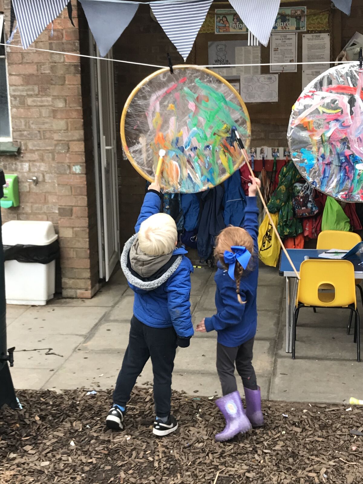 Children outside holding hoop wind catchers decorated with tissue paper