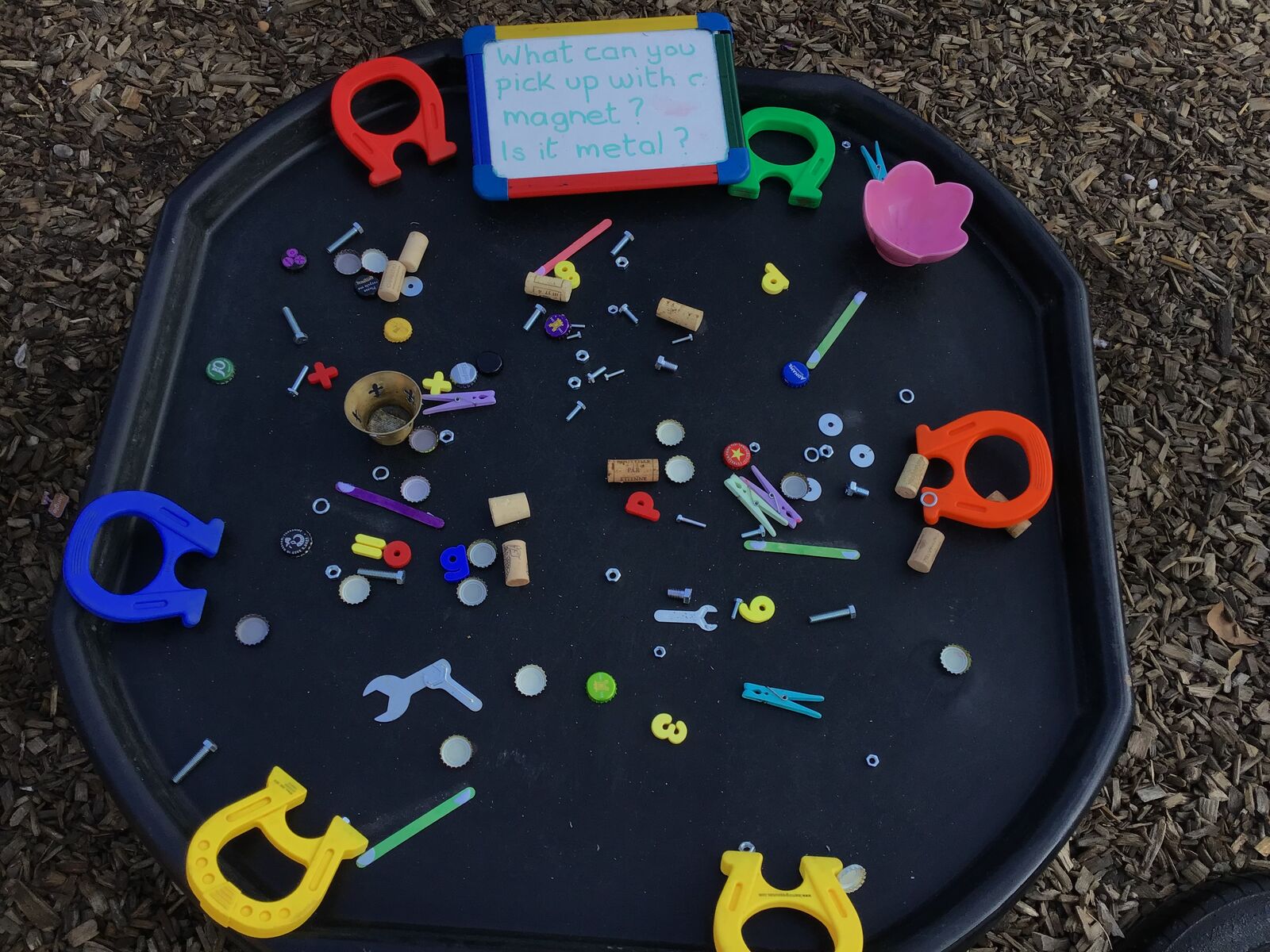 A tuff tray set up with magnetic letters and loose parts