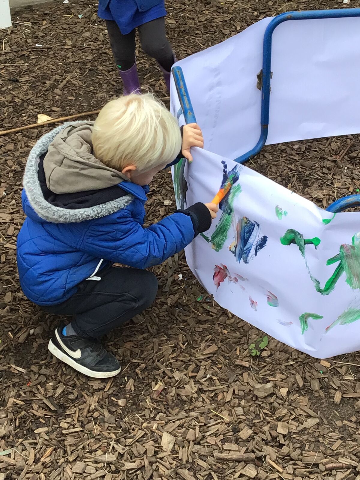 A child painting a large fabric banner outdoors