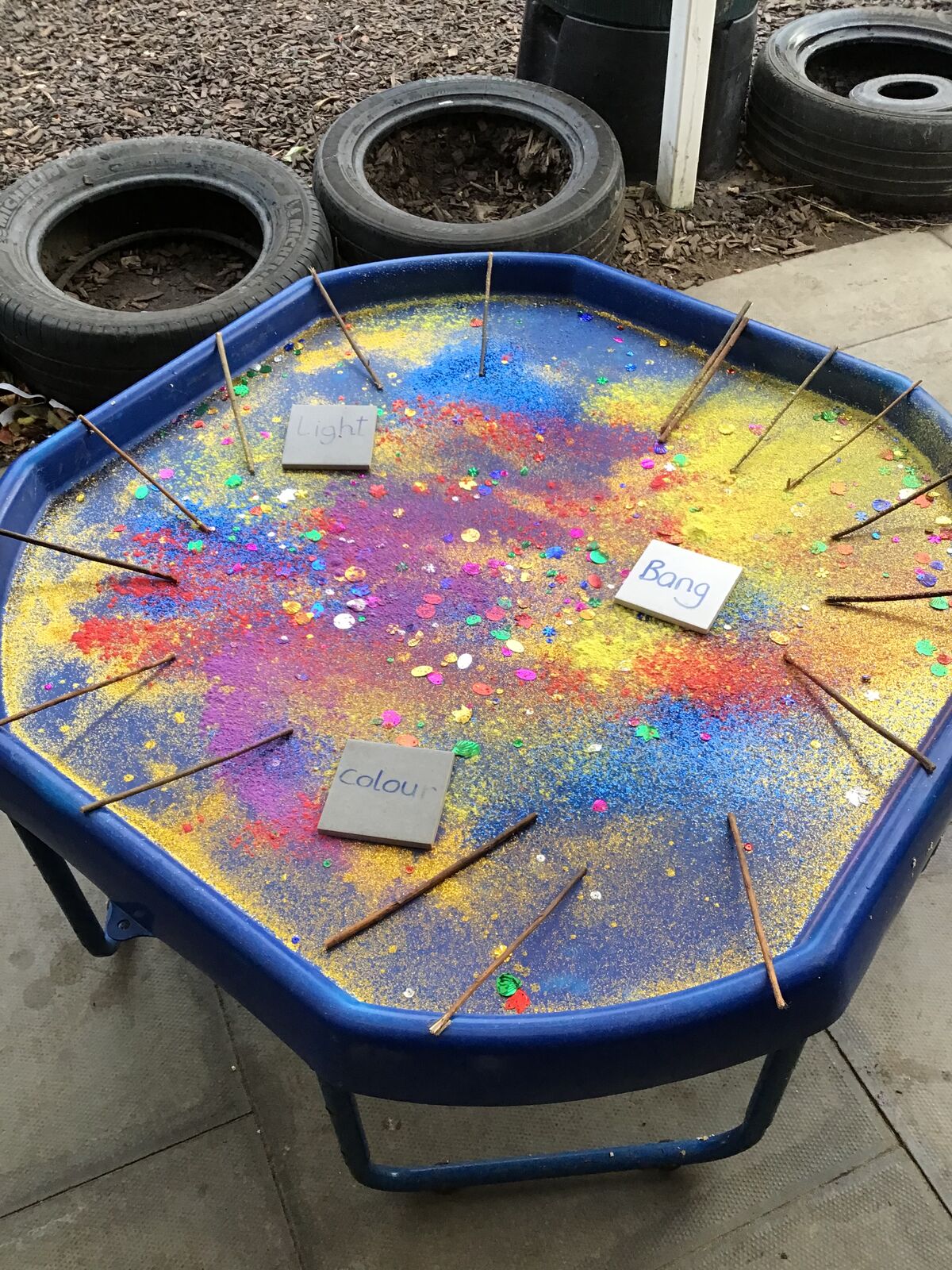 A tuff tray scattered with brightly coloured powder paint