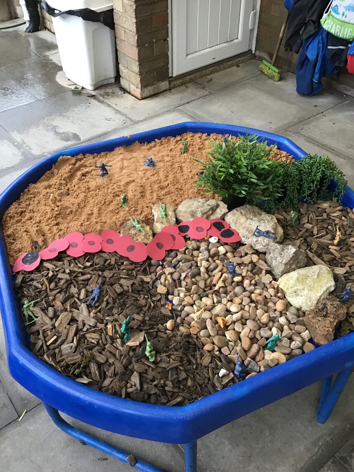 A digging tray of stones, bark and pebbles with a small planted mound