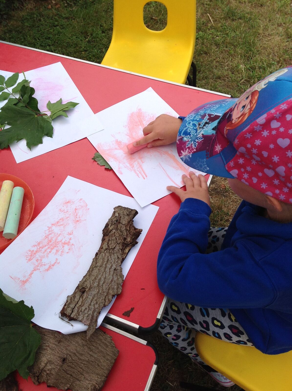 A child making bark and leaf rubbings with chalk on paper