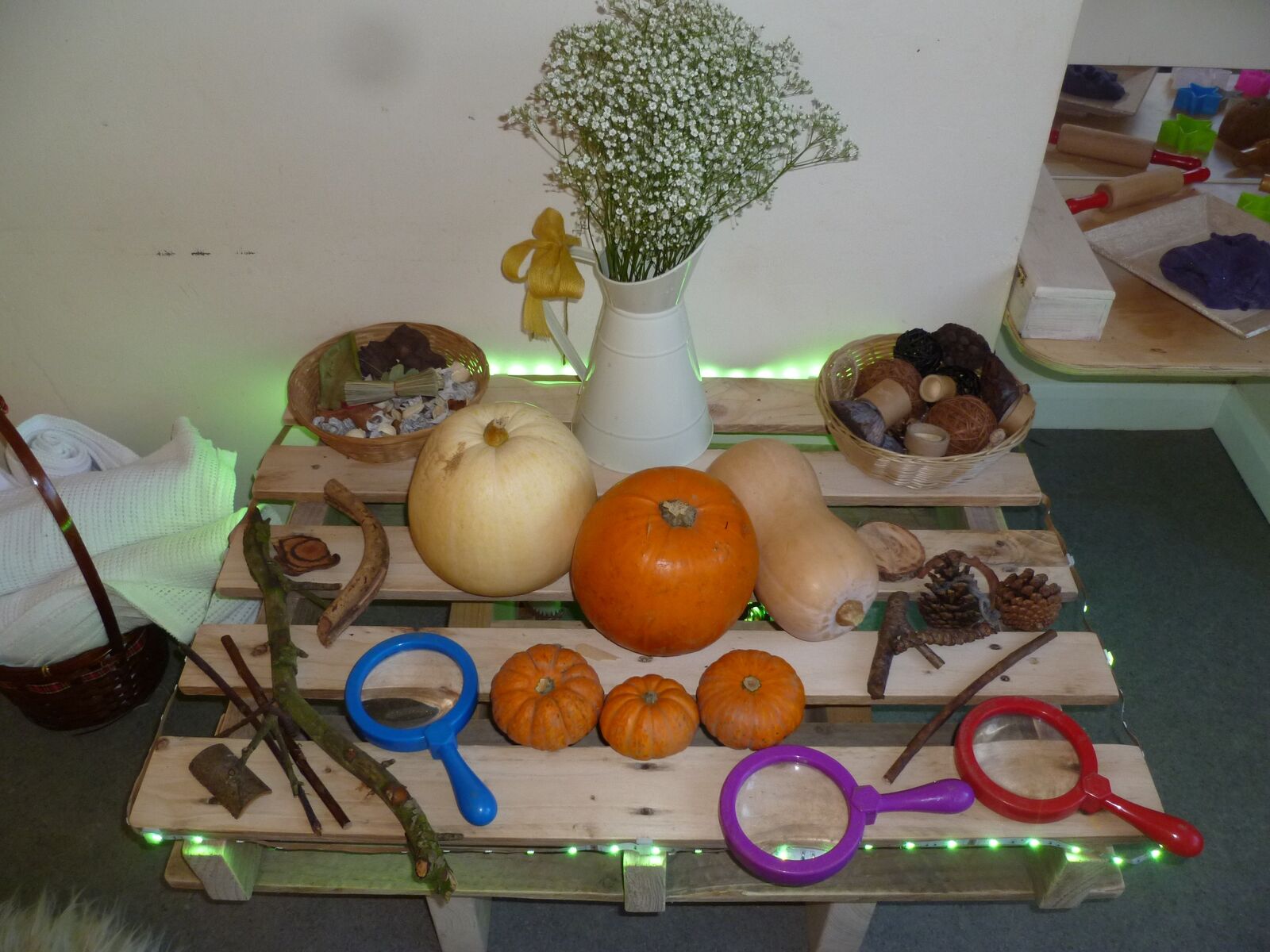 An autumn investigation table with pumpkins, nuts, sticks and magnifying glasses