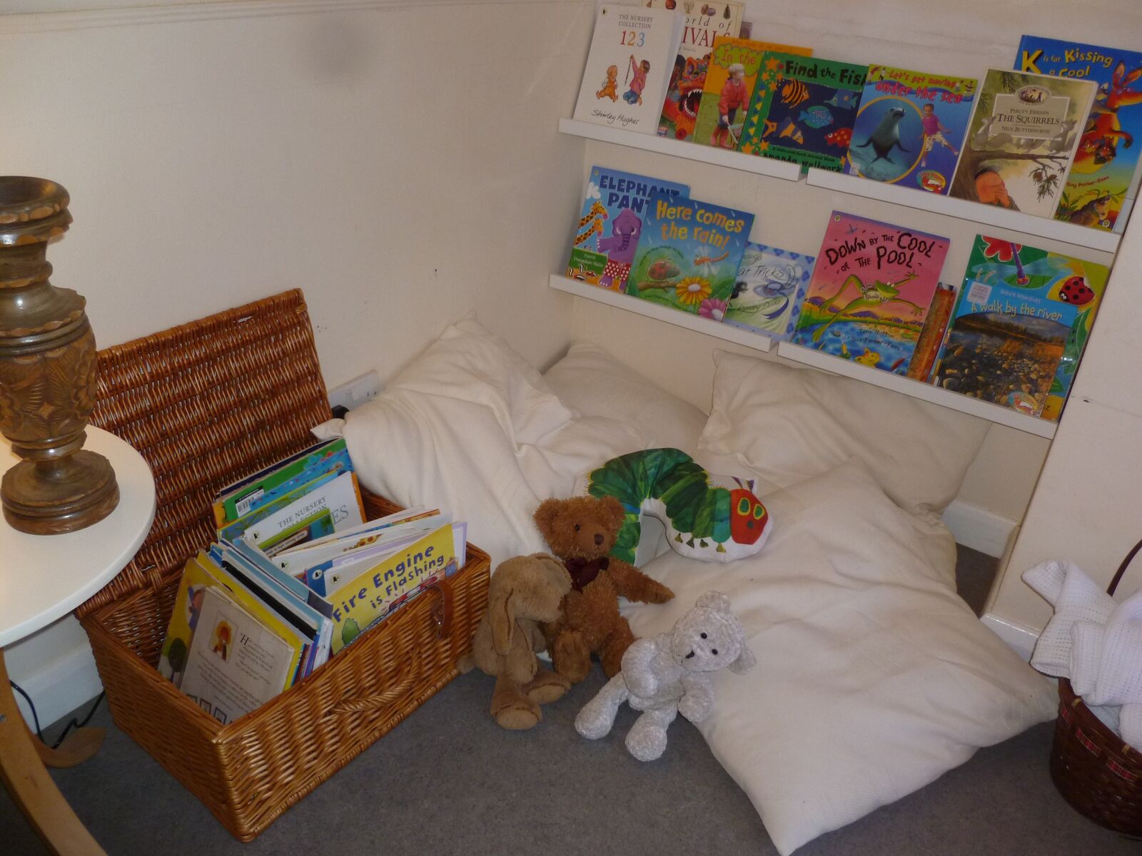 The book corner with cushions, soft toys and a basket of story books
