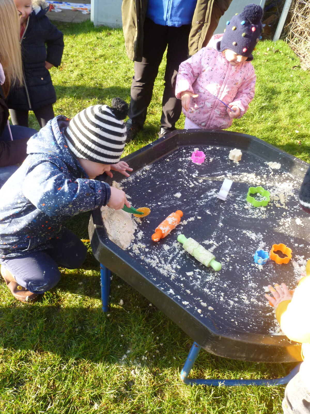Two children playing in shaving foam on a tuff tray in the garden