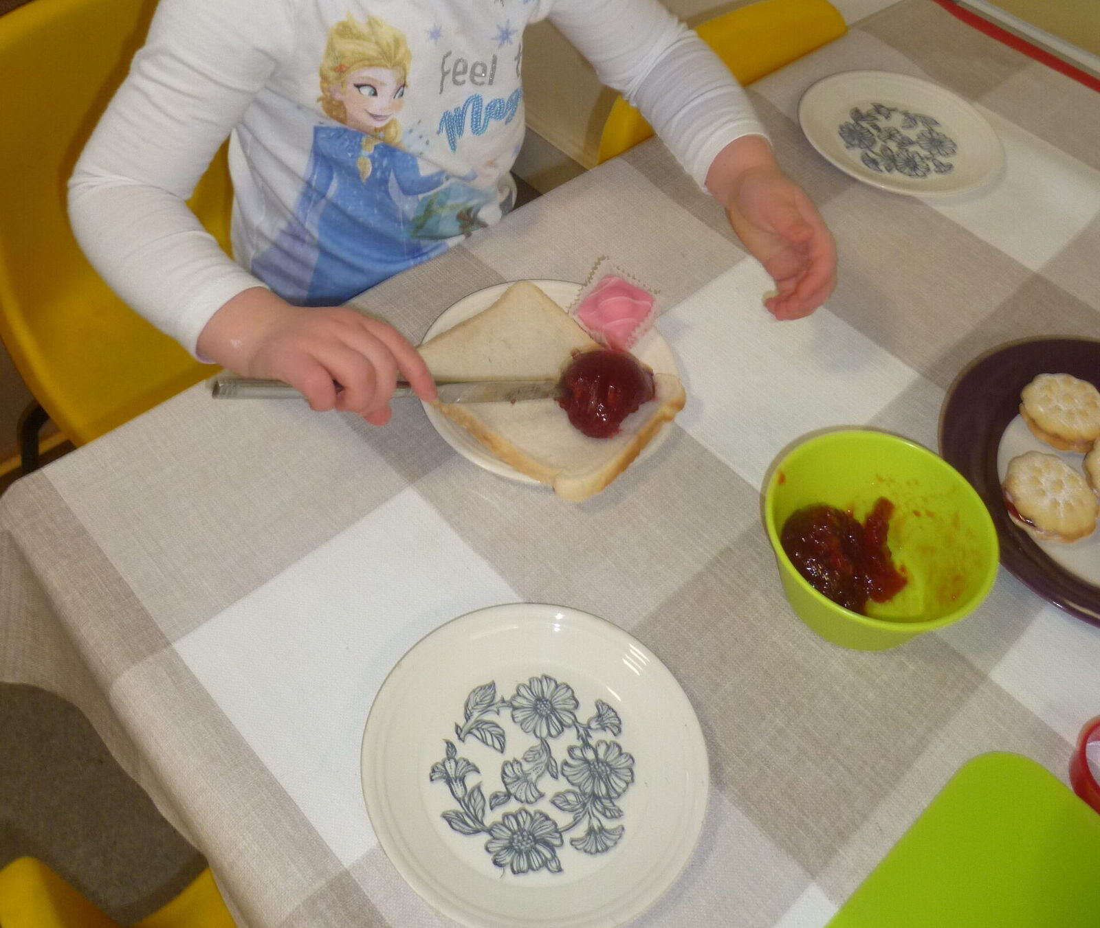 A child spreading jam to make their own sandwich