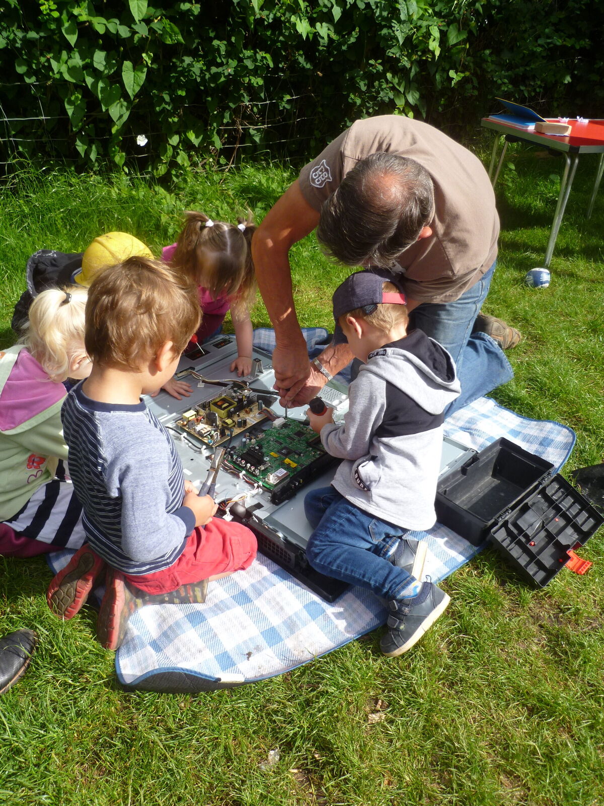 Children gathered around an adult planting in the garden
