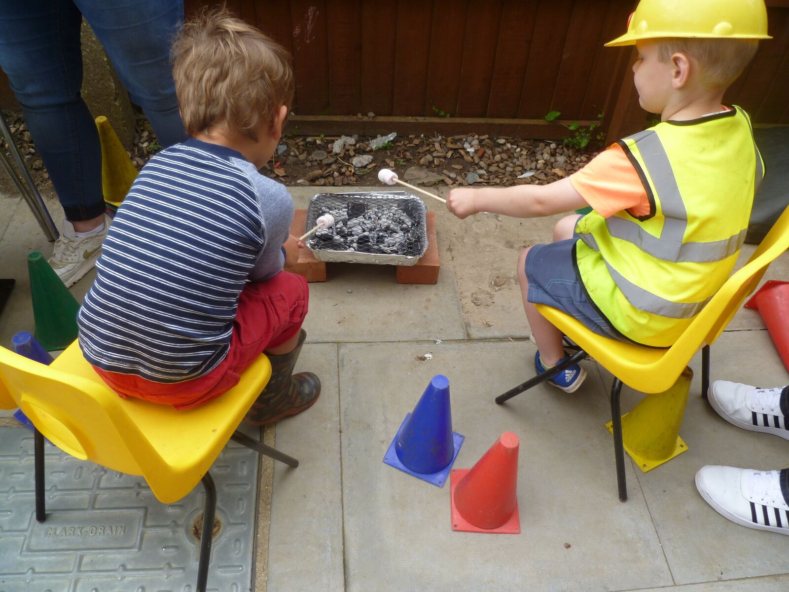 Two children sitting outside with trays of soil and seeds