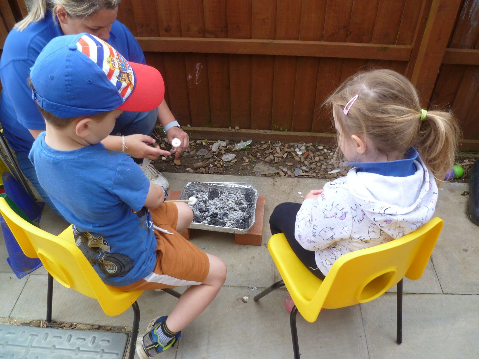 Children in high-vis waistcoats exploring trays of soil outdoors