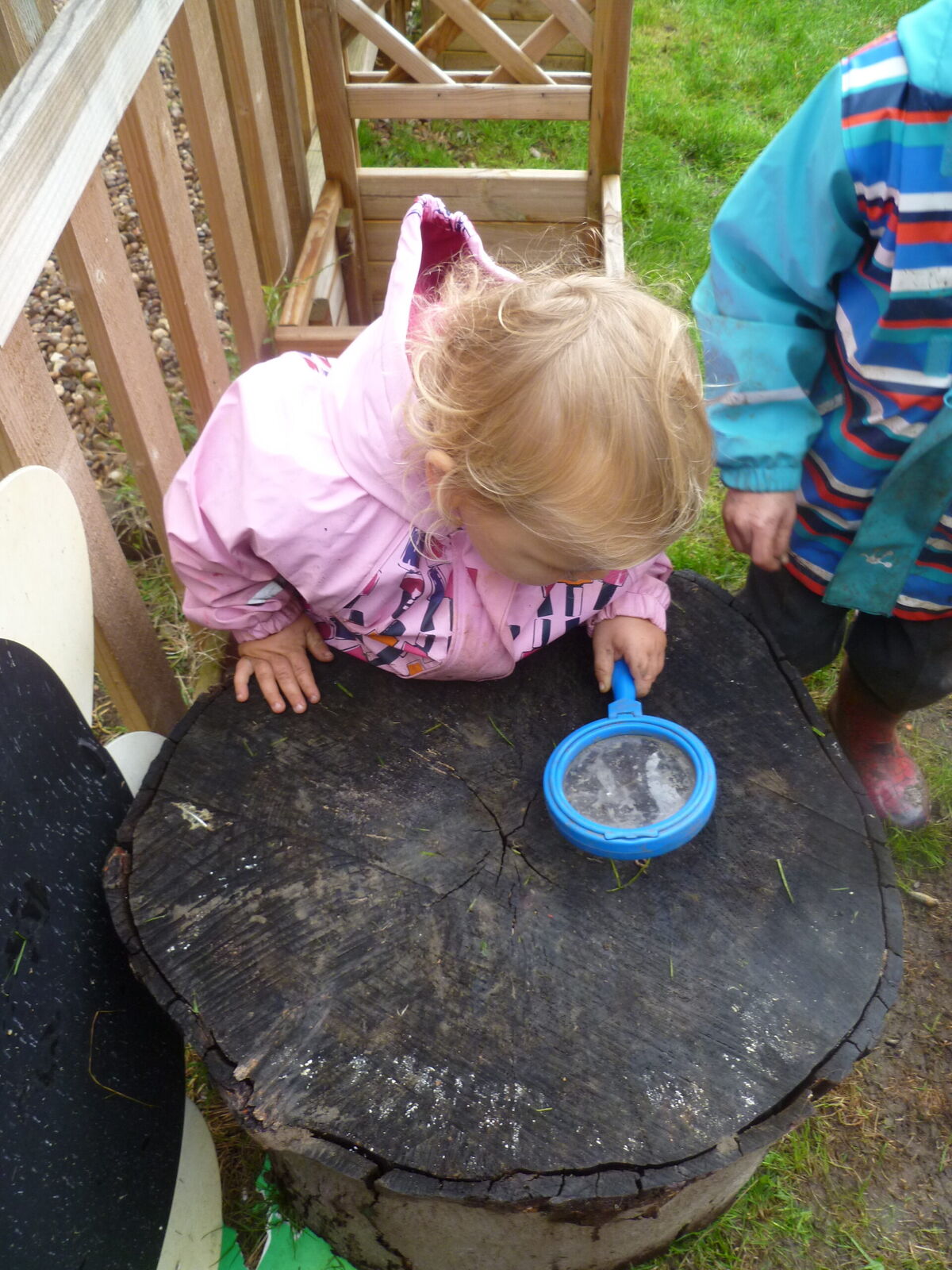 A child sieving on top of a large tree stump table