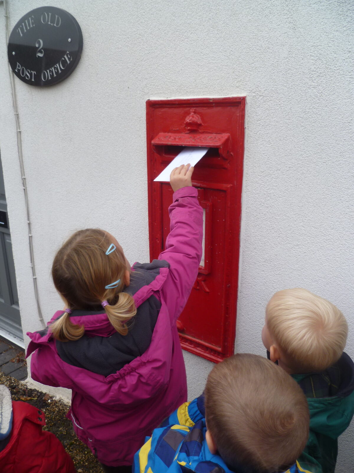 Children posting a letter into the village post box