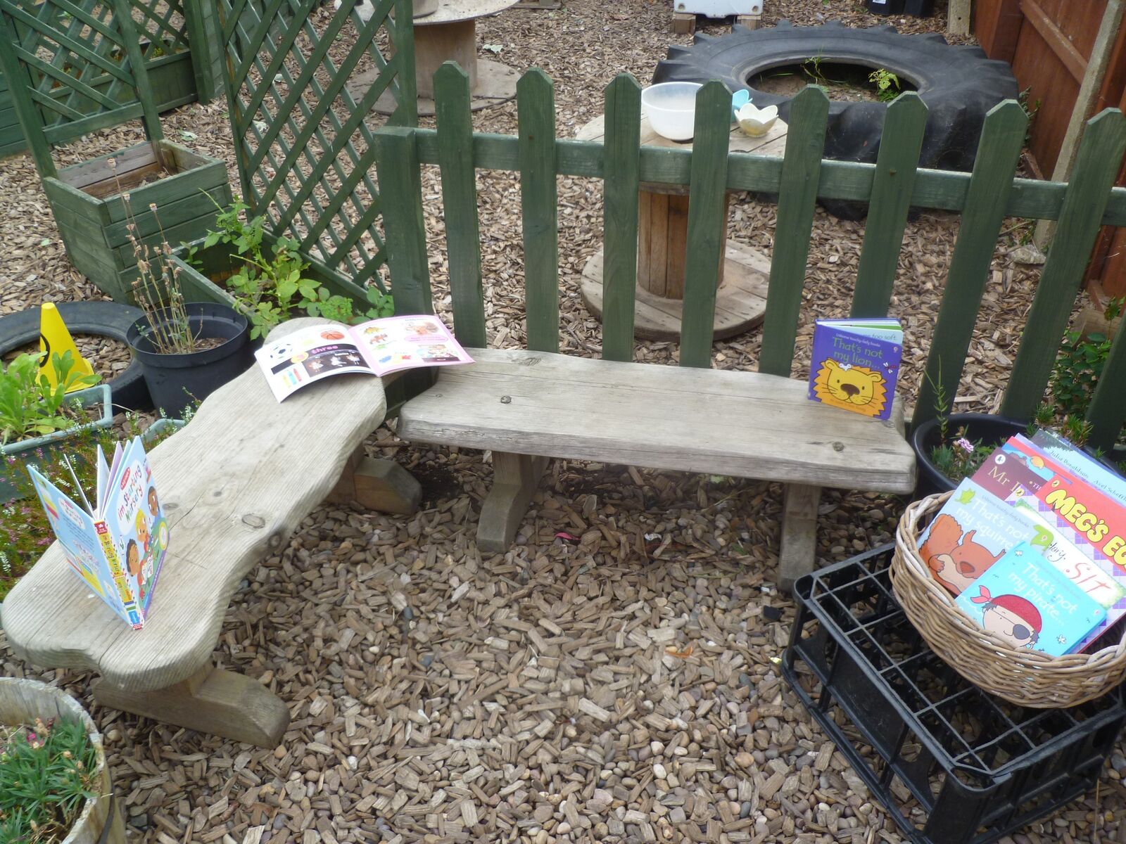 A wooden bench outdoors with story books and a crate of picture books