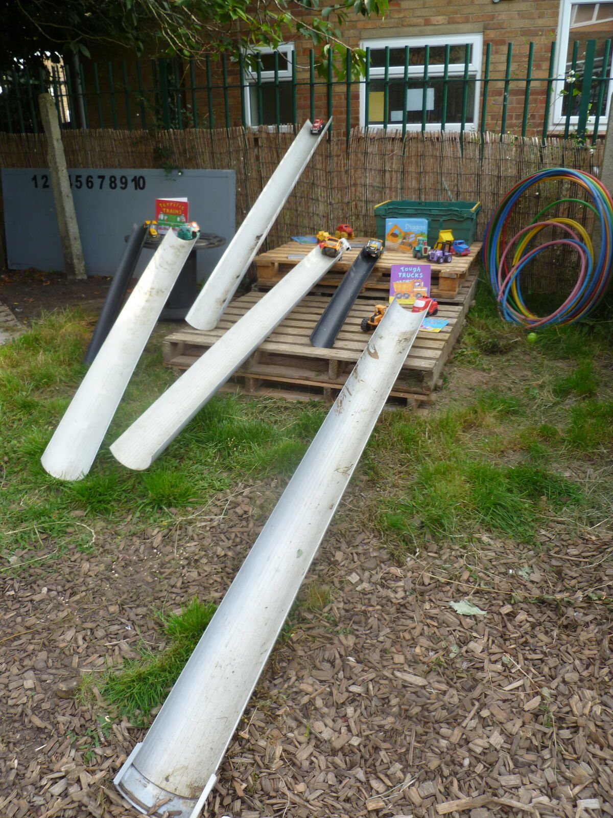 Long lengths of guttering laid out on the grass for water play