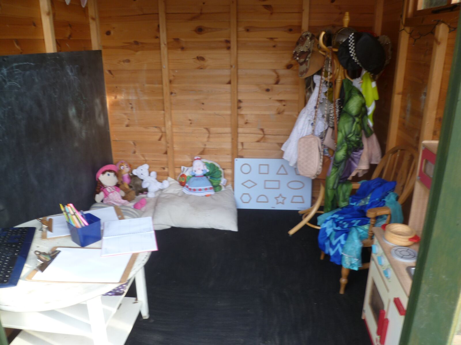 Inside the wooden playhouse with dressing up clothes and a chalkboard