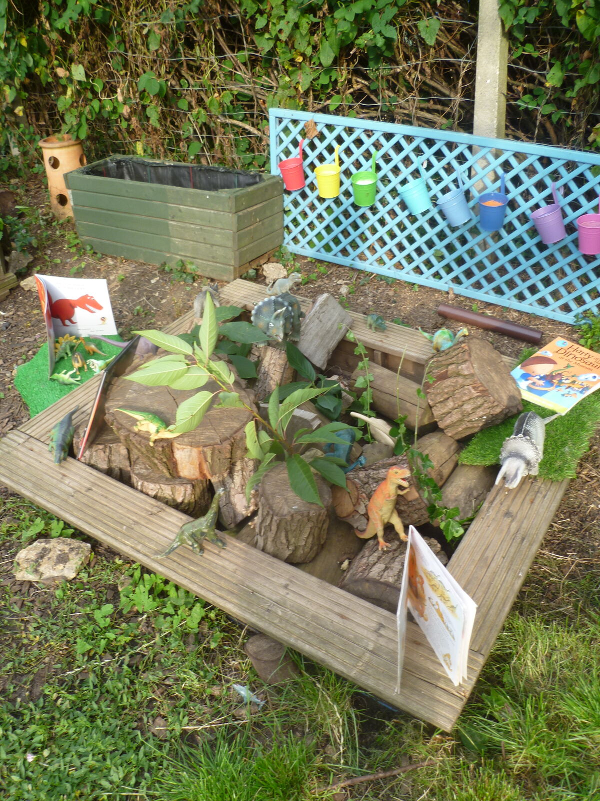 A dinosaur small world planted up with grasses and logs