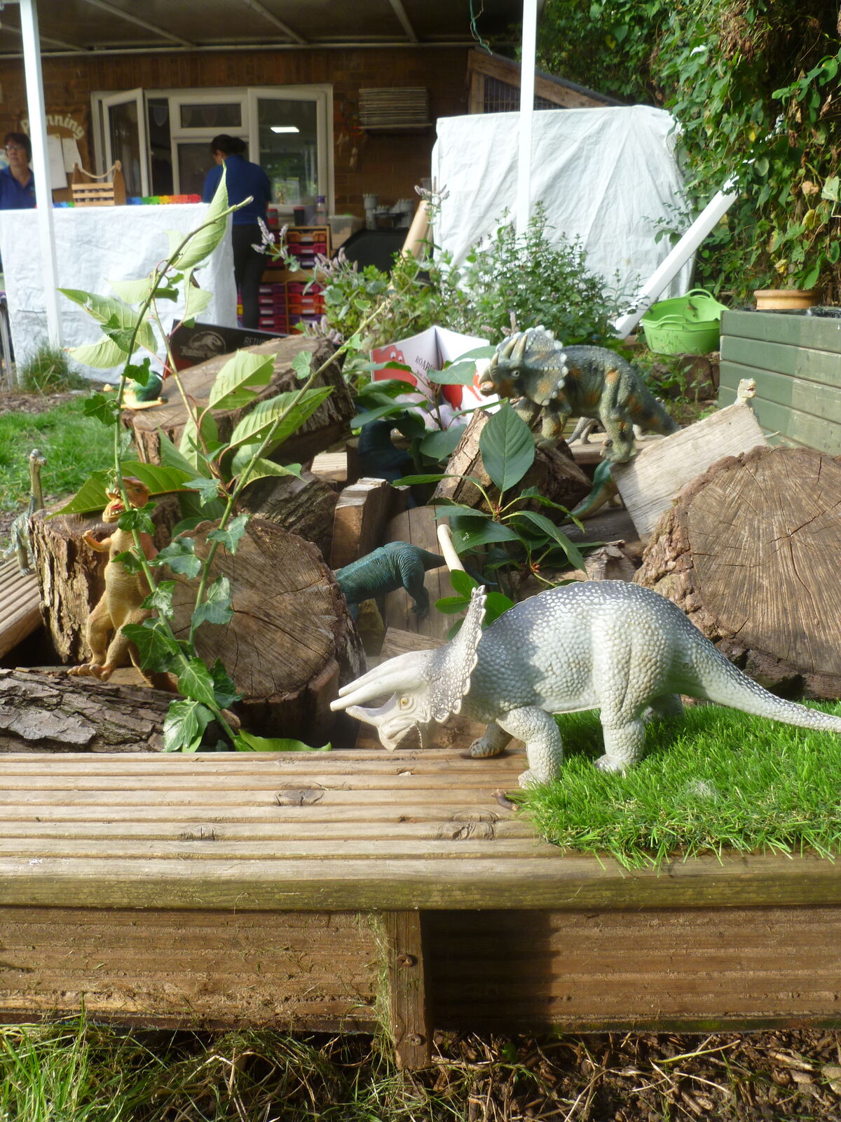 A raised planter turned into a dinosaur world with plants and stones