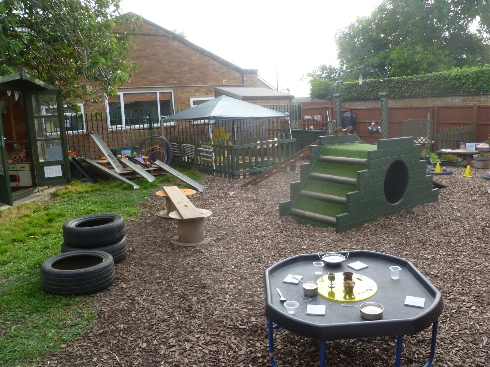 The outdoor play area with climbing steps, benches and a tuff tray
